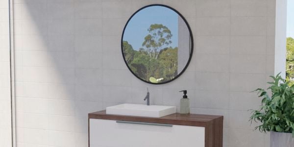 Bathroom with black framed mirror along with wash basin, plant and white wall tiles.