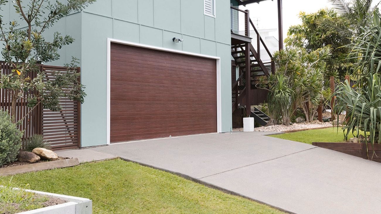 Garage entrance and driveway of a two-storey home featuring cladding painted in Dulux Milky Spearmint and Vivid White