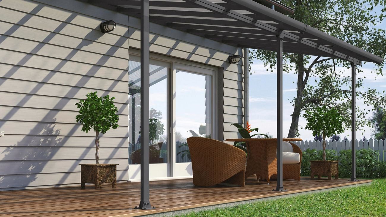 Two deck chairs and table on a deck outside a grey weatherboard house.