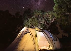 A lit up tent outdoors beneath the starry sky