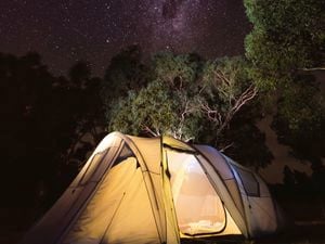A lit up tent outdoors beneath the starry sky