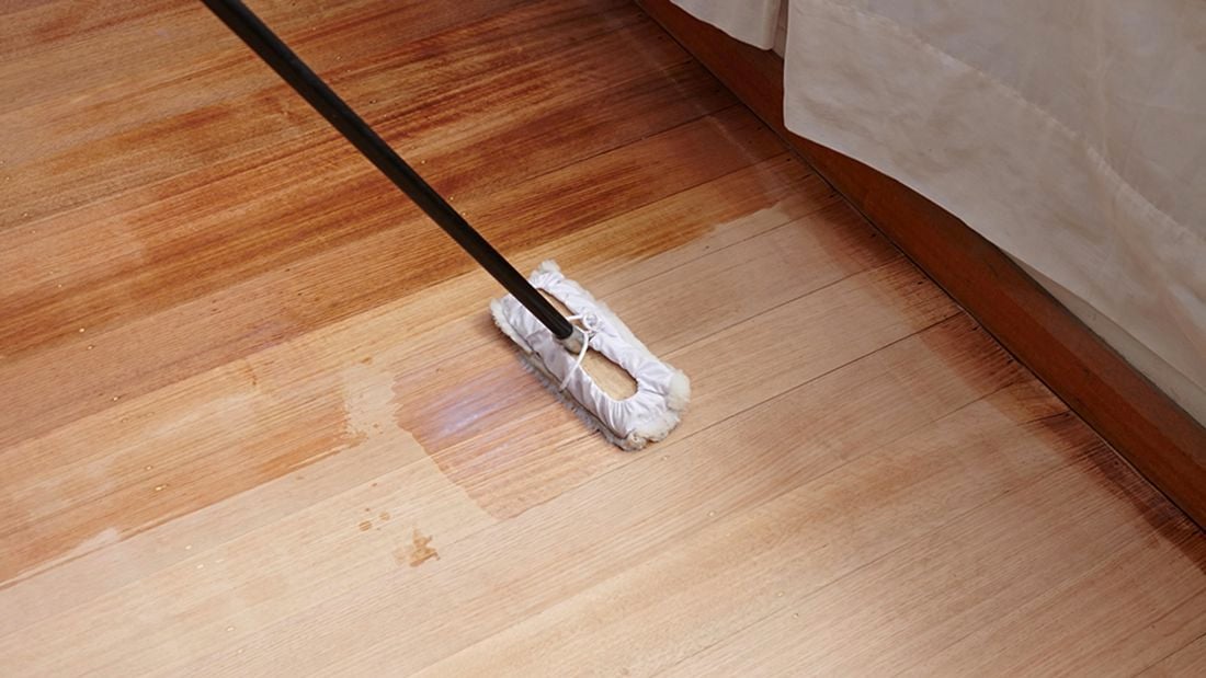 A lambswool applicator being used to apply sealer to a hardwood floor