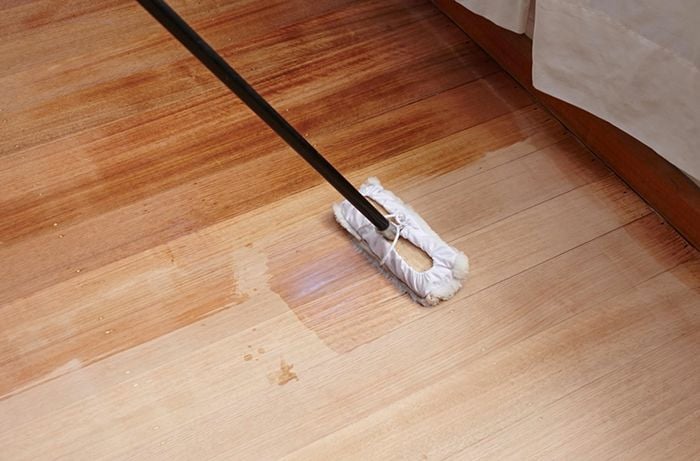 A lambswool applicator being used to apply sealer to a hardwood floor
