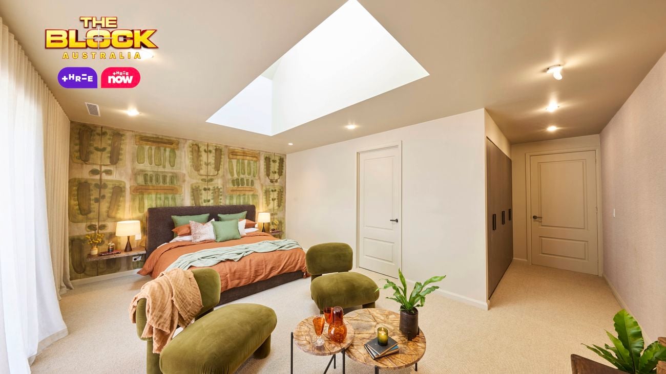  Modern bedroom with skylight, green velvet chairs, and earthy tones.