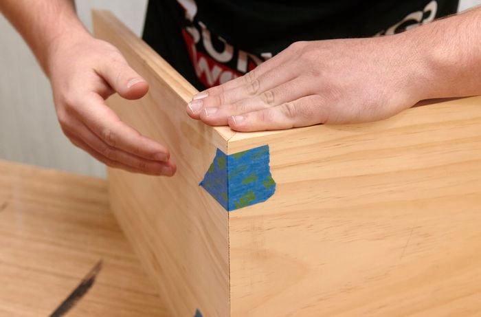 Person taping up edges of shadow box frame.