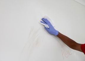 Cleaning a wall using a wipe. 
