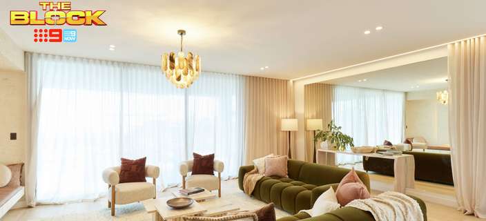 Contemporary living room featuring curved olive-green sofas, neutral armchairs, a chandelier and soft floor-to-ceiling curtains.