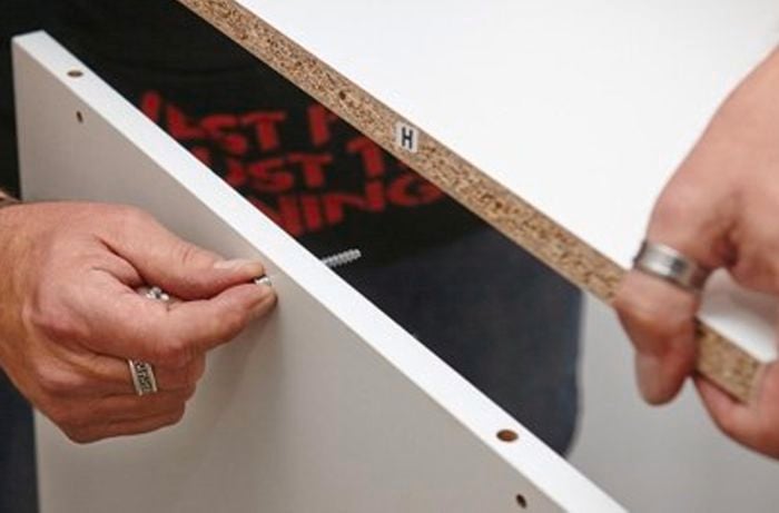 Inserting screws in the top of the wall.