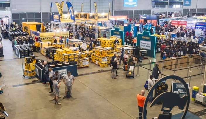 Wide overhead view of the Bunnings 2025 Sydney Trade Expo, showing busy exhibitor stands, power tools displays, and trade customers inside a large exhibition hall.