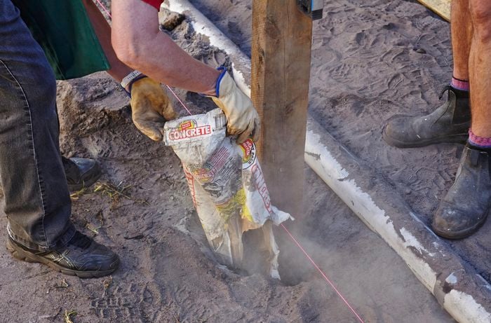A posthole being filled with concrete to set a fence post in place