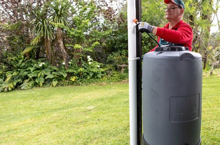 Bunnings employee attaches downpipe to rainwater tank
