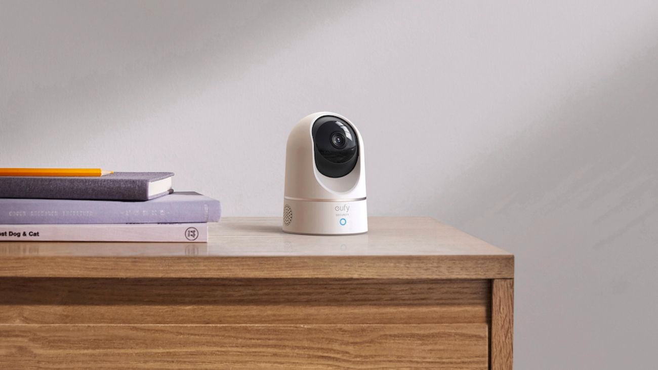 eufy indoor security camera on timber drawers next to a pile of books.
