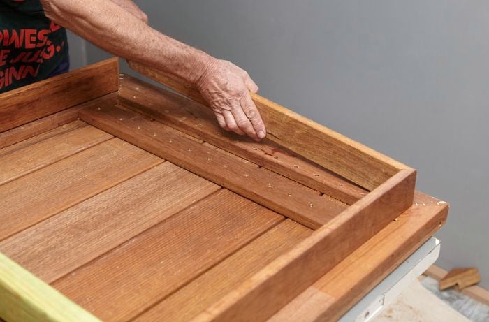 Person laying piece of timber into a table frame formation.