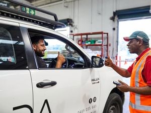 A Bunnings Warehouse team member and a tradie in a white ute give the thumbs up to each other