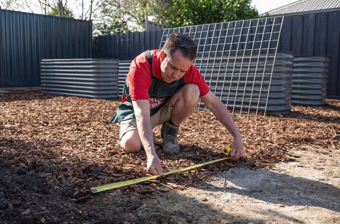 A Bunnings Team Member holding a tape measure just above the ground