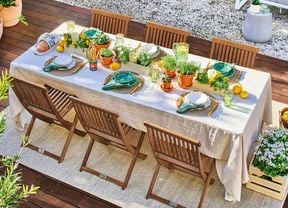 An outdoor timber dining setting with a decorated table laden with herb pots, place settings and lemons showcasing biophilic design.