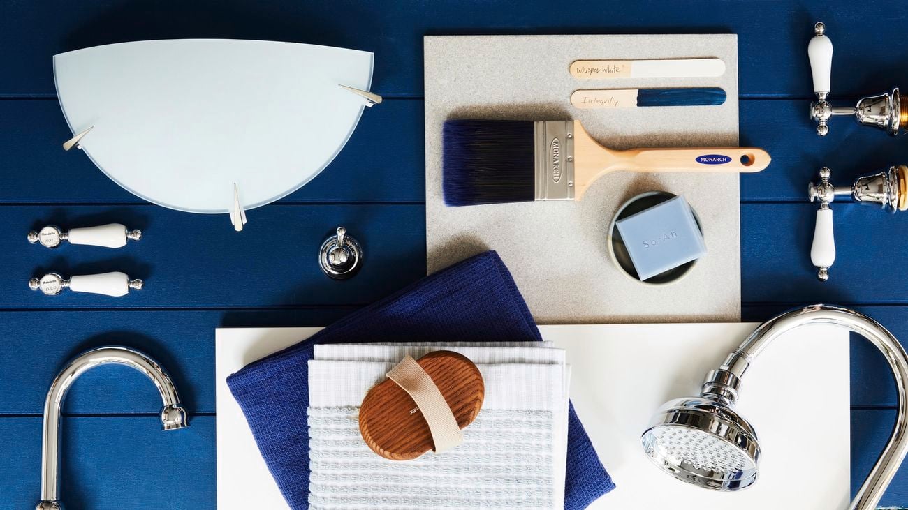 Hamptons-style bathroom fittings and accessories on a flatlay, featuring a blue VJ panel