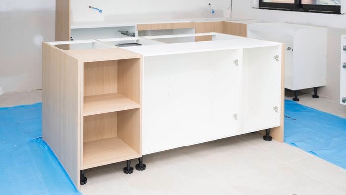 Kitchen cabinets are carefully placed on protective blue sheets to install the kitchen island.