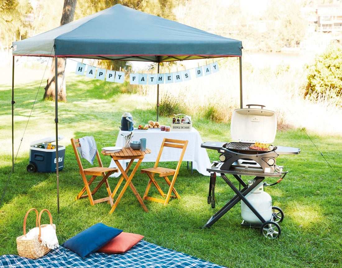 Outdoor picnic area with timber sun chairs, picnic table and happy fathers day banner