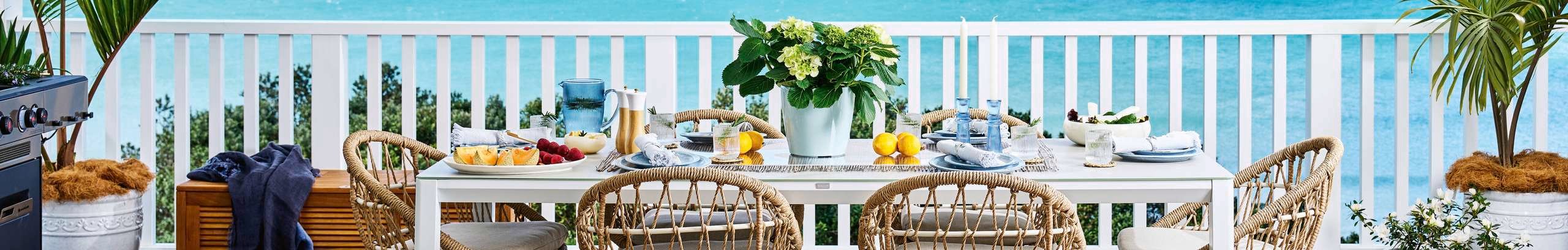 Styled outdoor dining setting on a balcony with beach views.