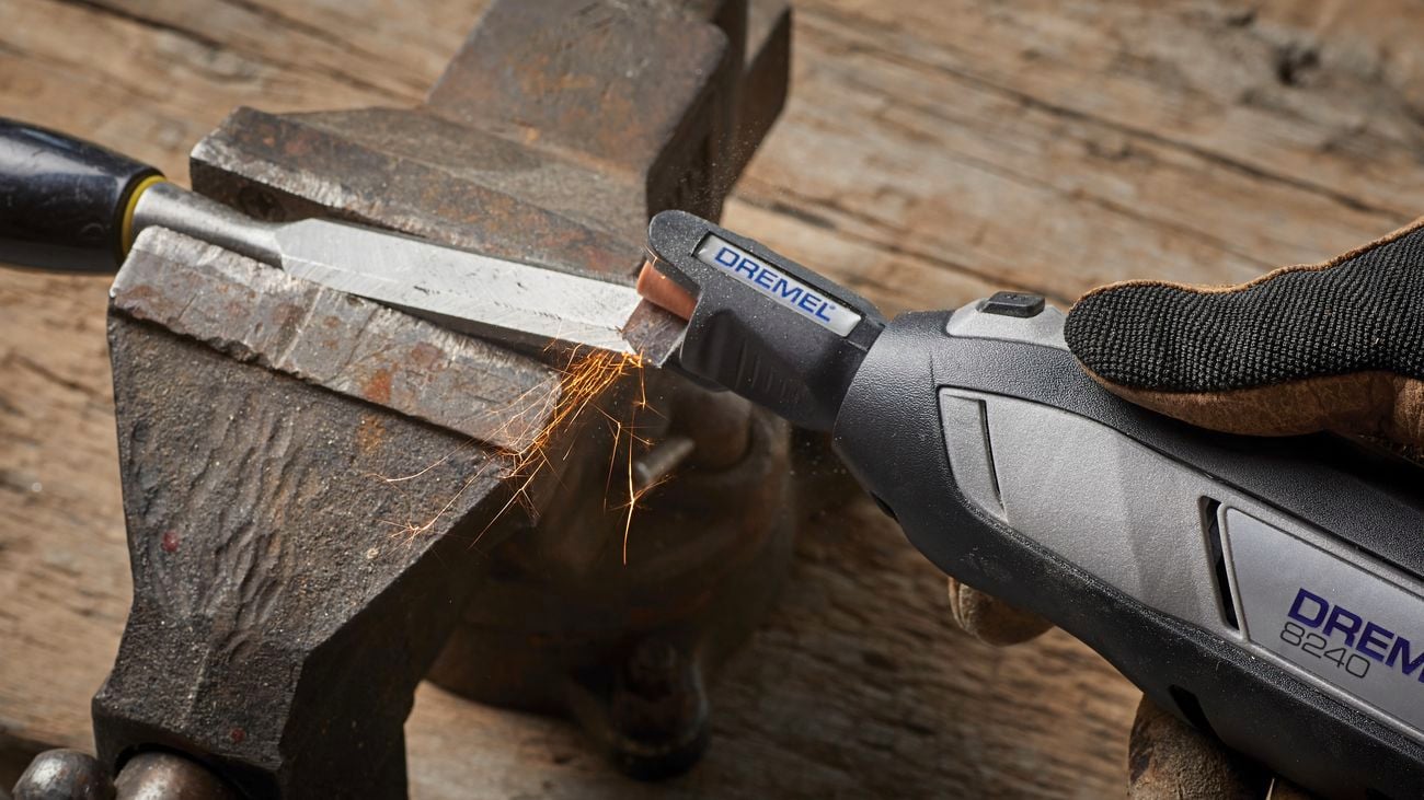 Dremel tool is sharpened using a sharpening tool on a wooden table