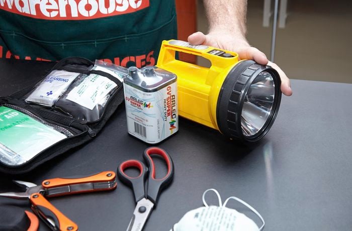 A heavy duty flashlight with large battery, scissors, facemask, first aid kit and Swiss army tool