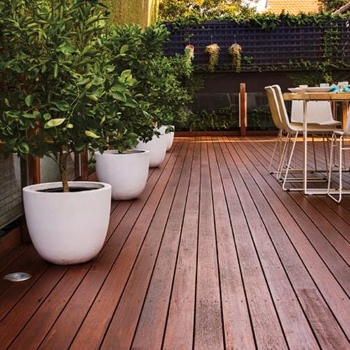 White pots with plants on decking, vertical garden and outdoor dining setting