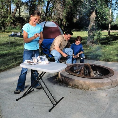 roasting marshmallows on a campfire while a woman puts them on a stick 