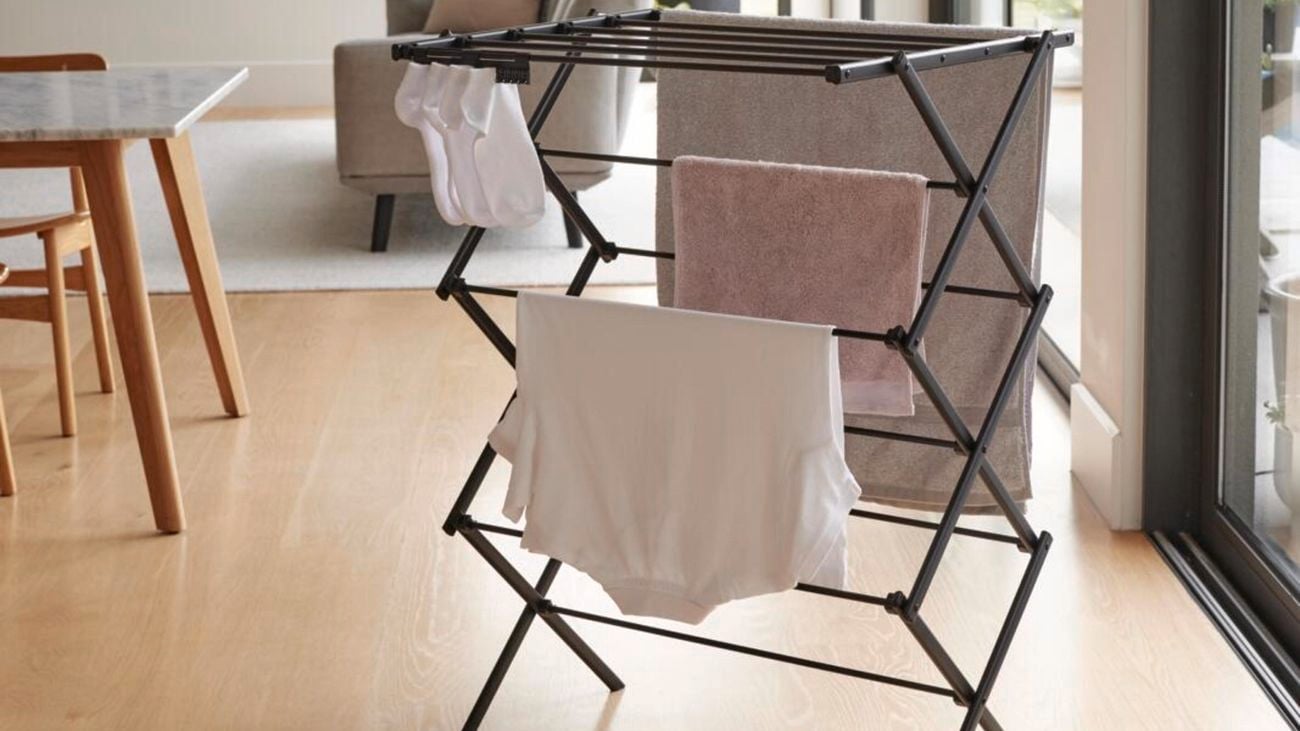 A clothes airer stands in the middle of a room with a towel hanging on it