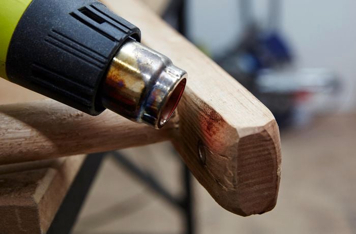 Person using a heat gun on DIY timber ladder to add to the distressed look.