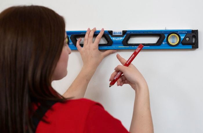 Person using a level to make marks on a wall
