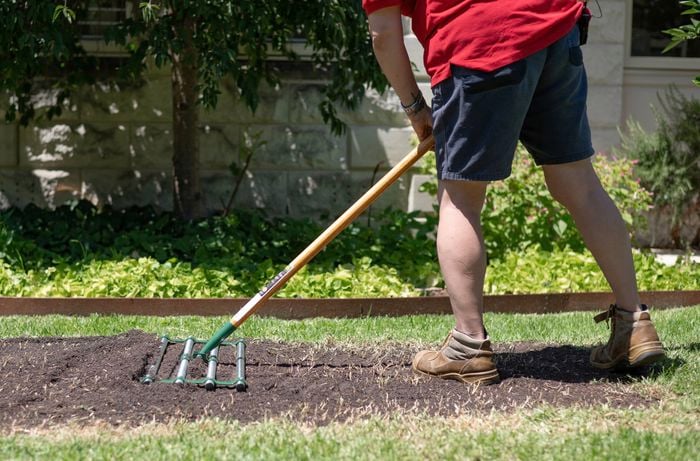 Holding a soil spreader.