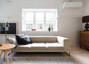 Styled living room featuring an air conditioner, beige sofa, timber coffee table and console