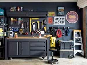 A garage with workbenches, storage cabinets, tools and old signs hanging on the walls.