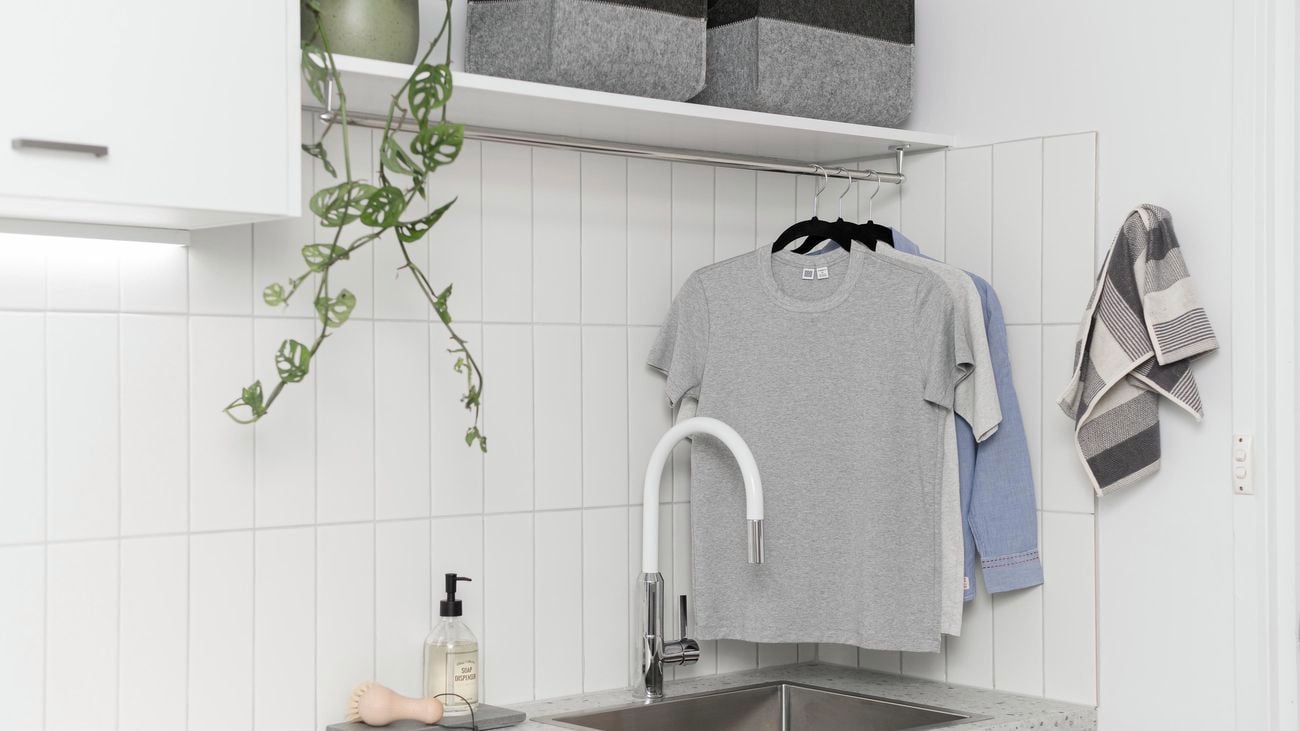 Laundry with clothing rail hanging above a sink.