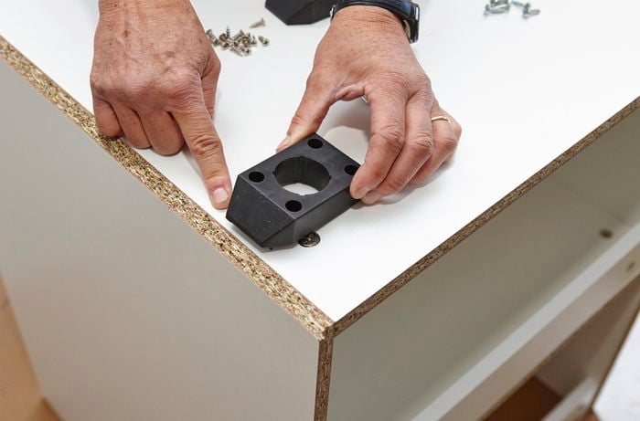 Person attaching base of feet to cupboard