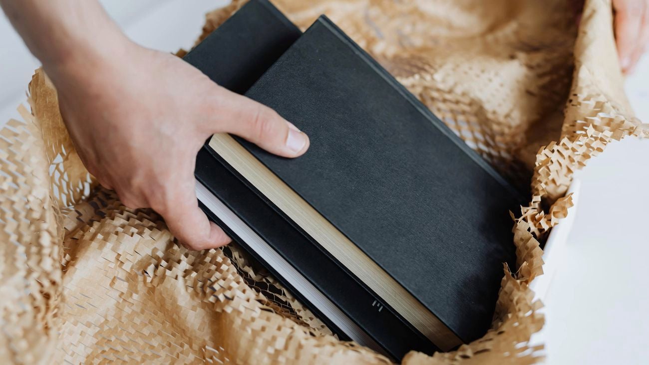 A person placing books into a box filled with Wrap & Move’s honeycomb paper wrap