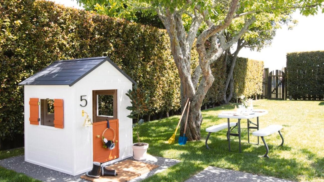 Green garden with tree, pinic table and cubby house.