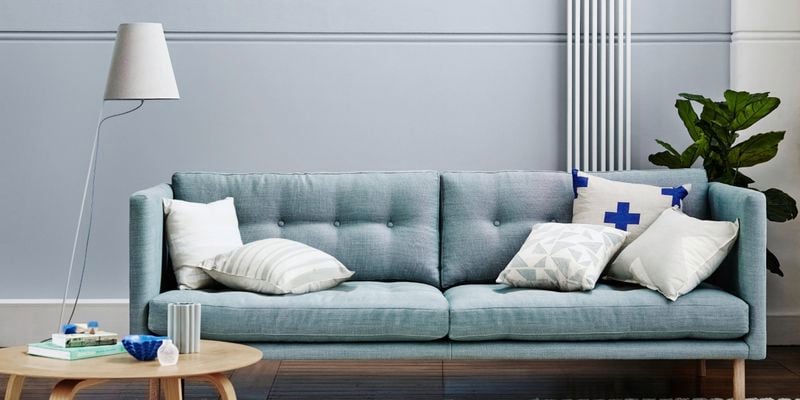 Lounge room featuring couch, coffee table, rug, lamp and fiddle leaf fig.