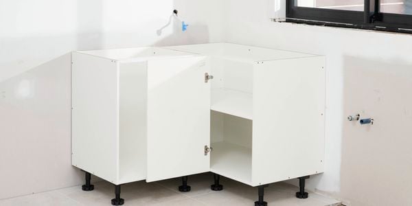 The image shows two assembled corner base cabinets installed side by side, with doors open to reveal internal shelving.