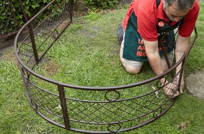 A Bunnings team member adding vertical supports to a garden archway