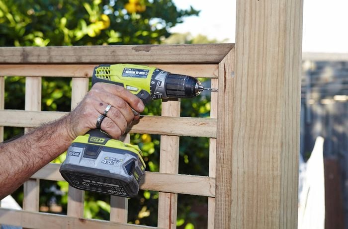 Perso drilling lattice fence to timber post.