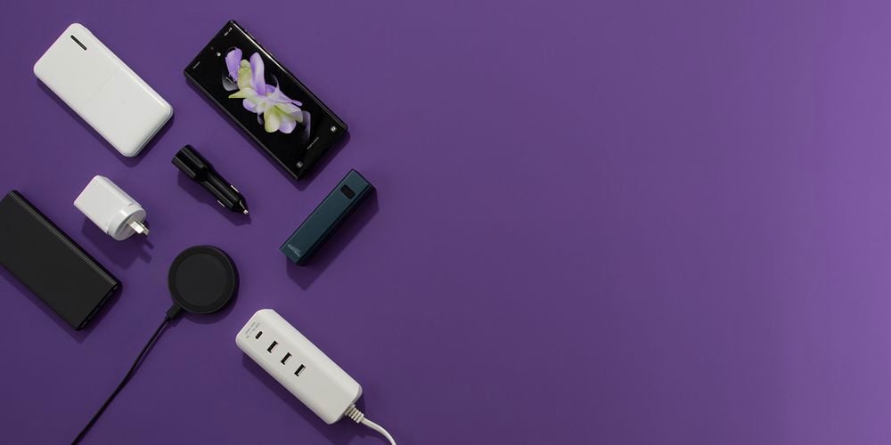 Purple background with various charging products and a phone laid out on left side