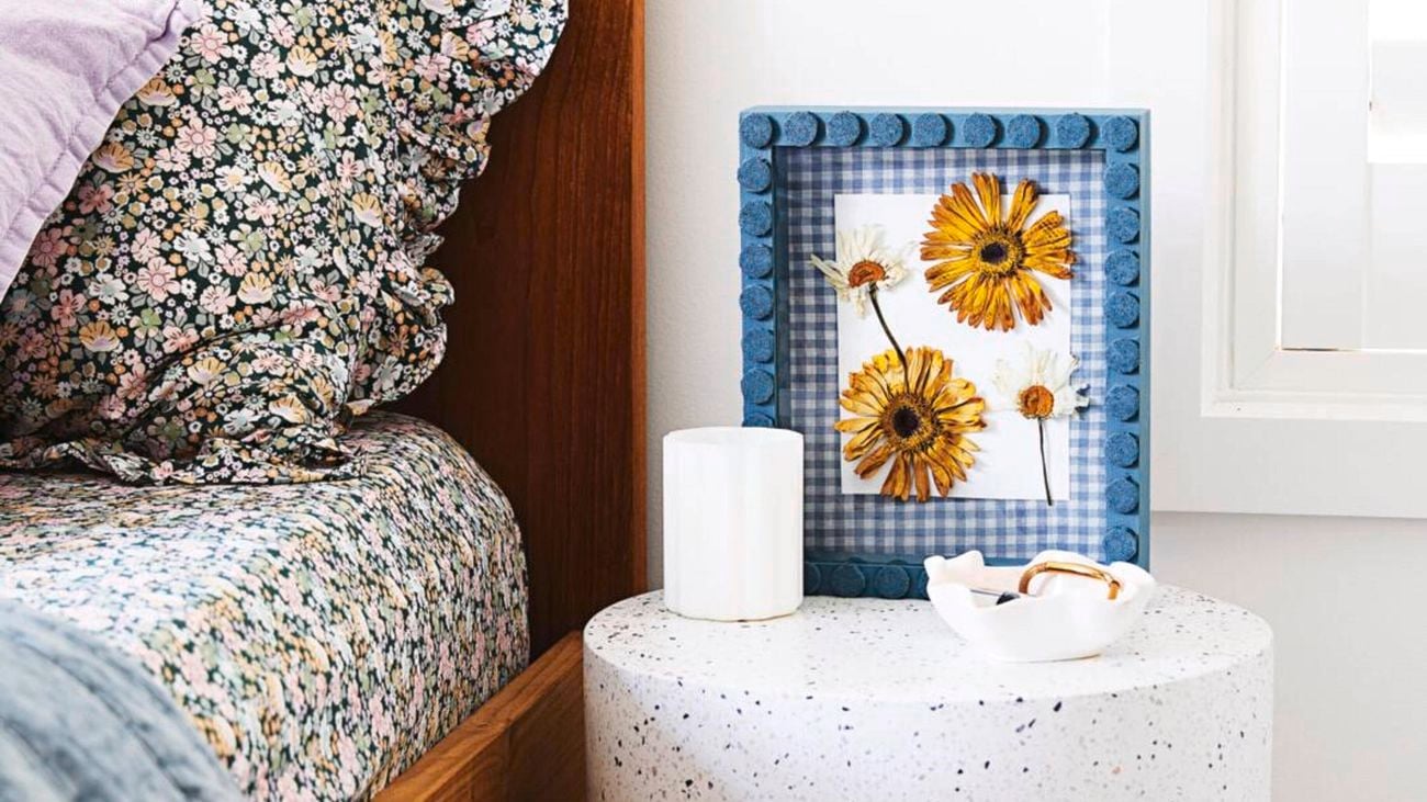 Granite cylinder table with a flower picture frame on top and a bed beside it