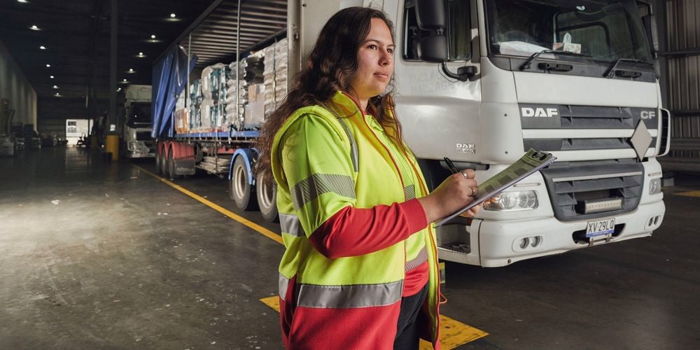 Woman in a high vis bunnings branded shirt looking at stock with clip board in hand
