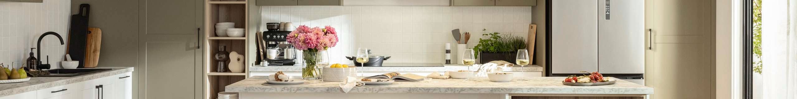 Neutral themed kitchen styled with stools, pendants, island benchtop and timber flooring .