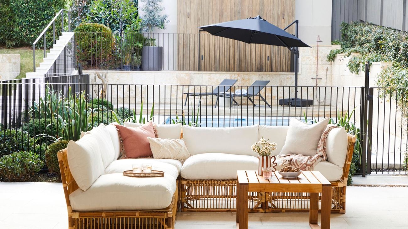 Outdoor lounge setting and coffee table on a patio in front of a swimming pool