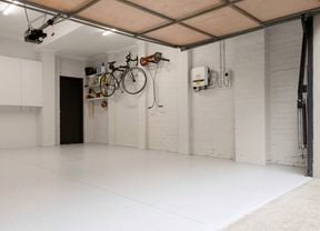 The image shows a garage with a floor, a wall-mounted cabinet, and a bicycle hanging on the other wall