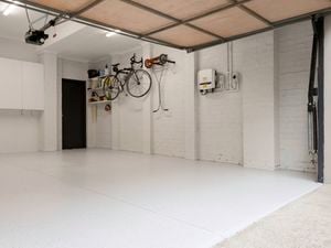 The image shows a garage with a floor, a wall-mounted cabinet, and a bicycle hanging on the other wall