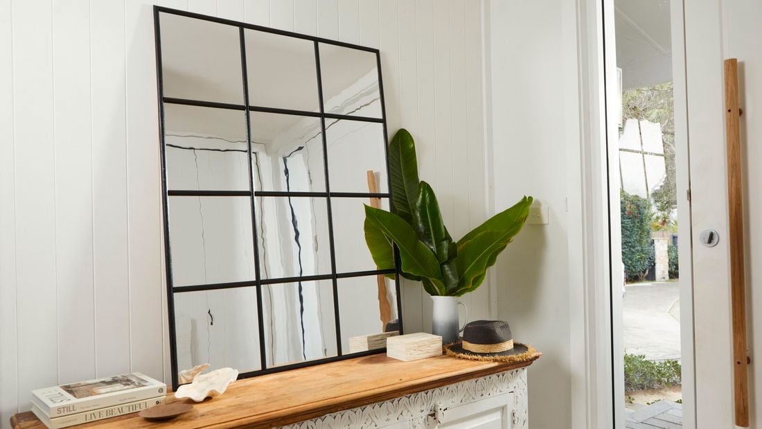 Newly made industrial grid mirror on table next to entrance.